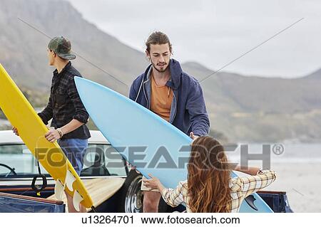 Young woman handing surfboard to man View Large Photo Image Stock Image - Young woman handing surfboard to man. Fotosearch