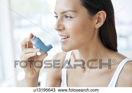 Stock Image - Young woman holding an inhaler. Fotosearch