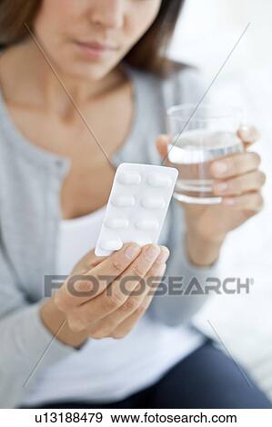Stock Photo - Young woman holding blister pack. Fotosearch