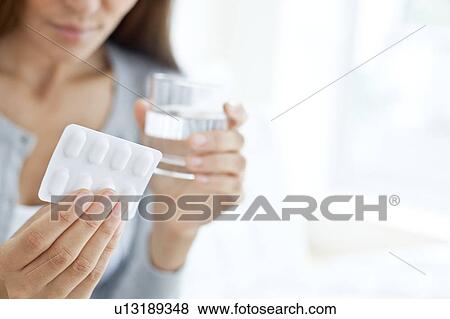 Stock Photo - Young woman holding blister pack. Fotosearch