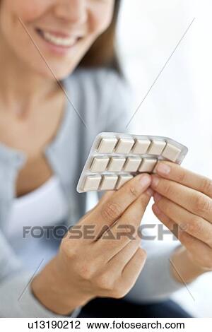 Stock Image - Young woman holding nicotine gum. Fotosearch