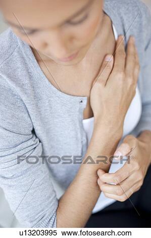 Stock Photography - Young woman scratching her arm. Fotosearch