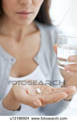 Picture - Young woman taking medicine. Fotosearch