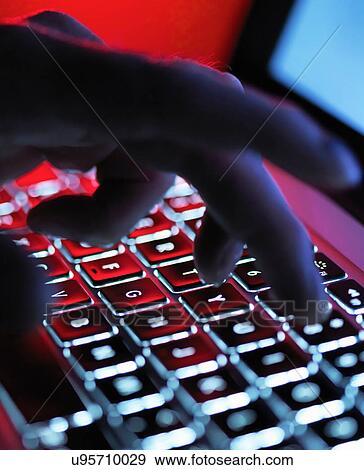A dark mystery hand typing on a laptop computer at night View Large Photo Image Stock Photo - A dark mystery hand typing on a laptop computer at night. Fotosearch