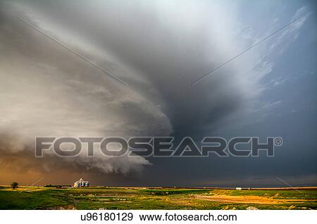 Stock Photo - A tornado-producing supercell thunderstorm spinning over ranch land at sunset near Leoti, Kansas. Fotosearch