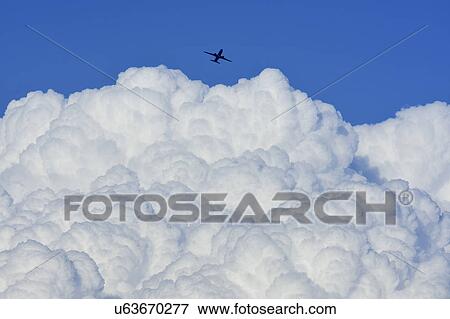 Airplane flying over large cloud View Large Photo Image Stock Photo - Airplane flying over large cloud. Fotosearch