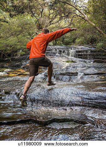 Stock Photo - Australia, New South Wales, Katoomba, Man running on rocks of Leura Cascade. Fotosearch