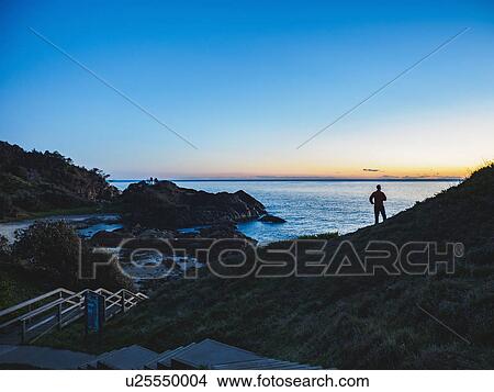 Picture - Australia, New South Wales, Port Macquarie, Silhouette of man looking at sea at sunrise. Fotosearch