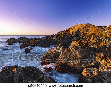Stock Photo - Australia, New South Wales, Port Macquarie, Lighthouse on rocky coat at sunrise. Fotosearch