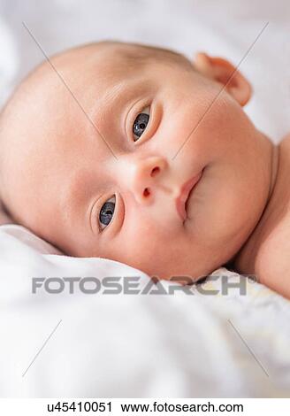 Stock Image - Baby boy (0-1 months) lying on bed. Fotosearch
