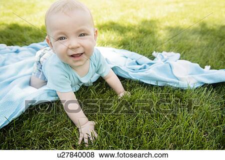 Stock Photo - Baby boy (6-11 months) crawling on grass. Fotosearch