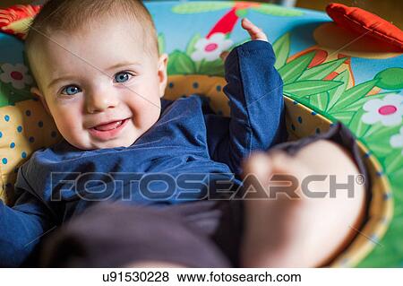 Stock Photo - Baby girl in baby seat looking at camera smiling. Fotosearch