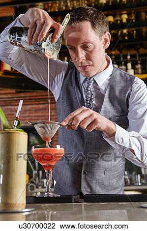 Stock Image - Bartender pouring cocktail. Fotosearch
