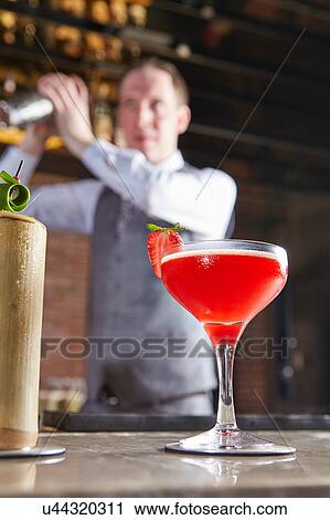 Stock Image - Bartender shaking cocktail shaker. Fotosearch