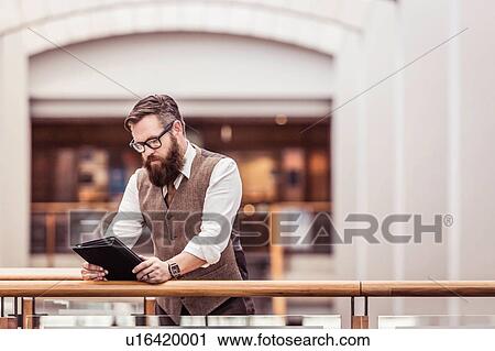Bearded businessman wearing tweed waistcoat reading digital tablet on office balcony View Large Photo Image Stock Image - Bearded businessman wearing tweed waistcoat reading digital tablet on office balcony. Fotosearch