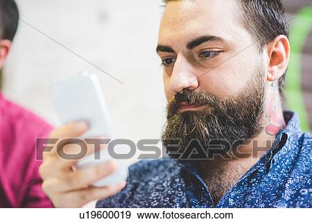 Stock Photo - Bearded young man using cellphone. Fotosearch