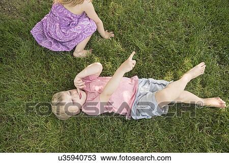 Boy (4-5) and girl (2-3) lying on grass View Large Photo Image Stock Image - Boy (4-5) and girl (2-3) lying on grass. Fotosearch