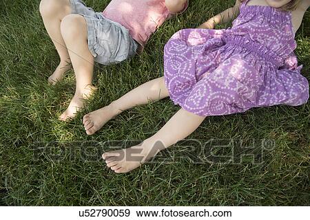 Boy (4-5) and girl (2-3) lying on grass View Large Photo Image Stock Photo - Boy (4-5) and girl (2-3) lying on grass. Fotosearch