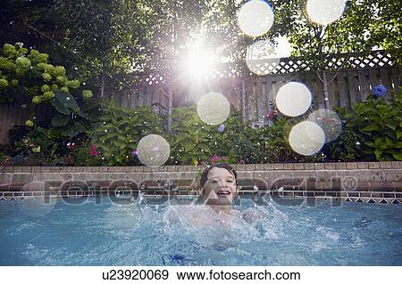 Stock Photo - Boy (4-5) playing in pool. Fotosearch