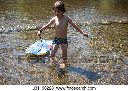 Stock Photo - Boy ankle deep in water with body board. Fotosearch