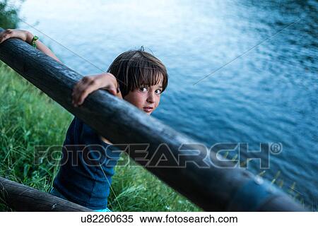 Stock Photography - Boy by river looking over shoulder at camera. Fotosearch
