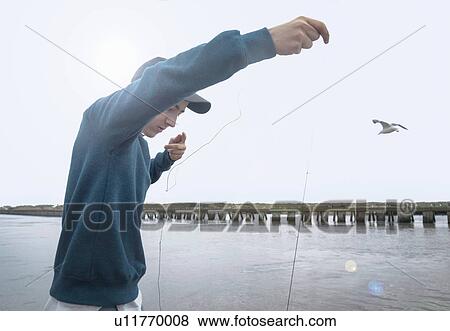 Stock Photo - Boy fishing by pier, Southwold, Suffolk, UK. Fotosearch