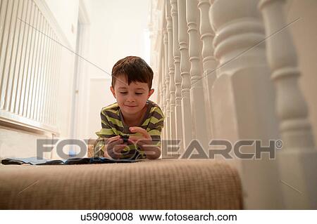 Boy lying at staircase playing with toys View Large Photo Image Stock Photo - Boy lying at staircase playing with toys. Fotosearch