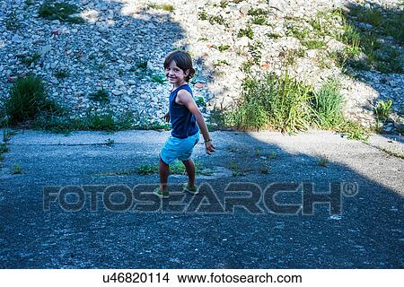 Picture - Boy on embankment looking at camera smiling. Fotosearch