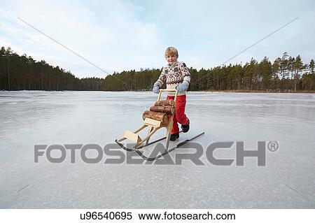 Boy pushing logs on kicksled across frozen lake, Gavle, Sweden View Large Photo Image Stock Photography - Boy pushing logs on kicksled across frozen lake, Gavle, Sweden. Fotosearch