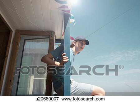 Boy sitting on balcony railing looking into distance View Large Photo Image Stock Photo - Boy sitting on balcony railing looking into distance. Fotosearch