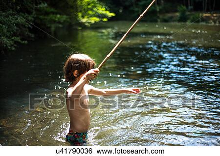 Stock Photograph - Boy waist deep in water holding stick. Fotosearch