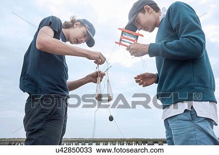 Stock Image - Boys preparing fishing equipment. Fotosearch