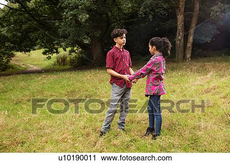 Stock Image - Brother and sister outdoors, holding hands. Fotosearch