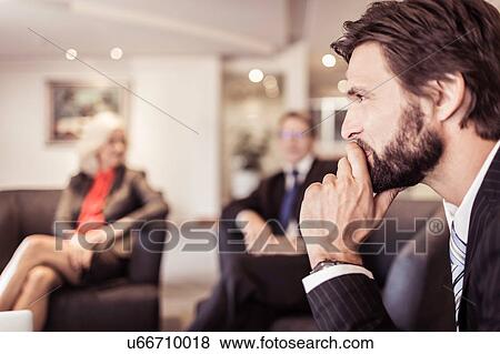 Businessman at meeting with hand on chin View Large Photo Image Stock Photo - Businessman at meeting with hand on chin. Fotosearch