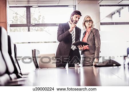 Businessman explaining to businesswoman in boardroom View Large Photo Image Picture - Businessman explaining to businesswoman in boardroom. Fotosearch