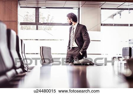 Stock Photography - Businessman looking through boardroom window. Fotosearch