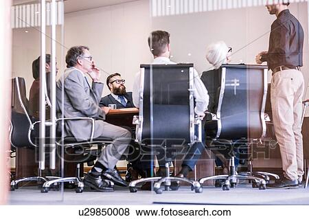 Stock Photo - Businessman making presentation to team in board meeting. Fotosearch