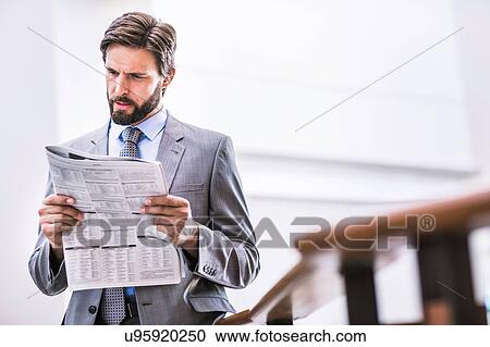 Stock Image - Businessman reading newspaper on office balcony. Fotosearch