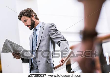 Stock Photo - Businessman reading newspaper on office balcony. Fotosearch