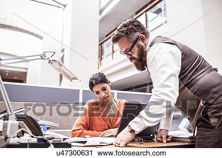 Stock Image - Businessman reading paperwork on office desk. Fotosearch