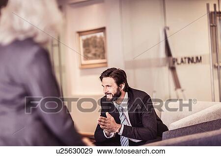 Businessman sitting in armchair talking to businesswoman View Large Photo Image Stock Photo - Businessman sitting in armchair talking to businesswoman. Fotosearch