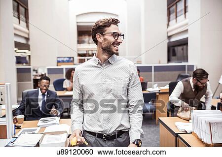 Businessman with banana looking over his shoulder in office View Large Photo Image Stock Image - Businessman with banana looking over his shoulder in office. Fotosearch