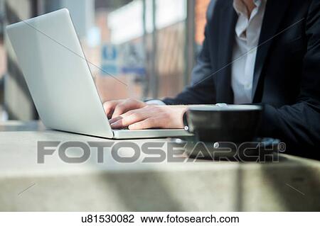 Stock Image - Businessman working with laptop in cafe. Fotosearch