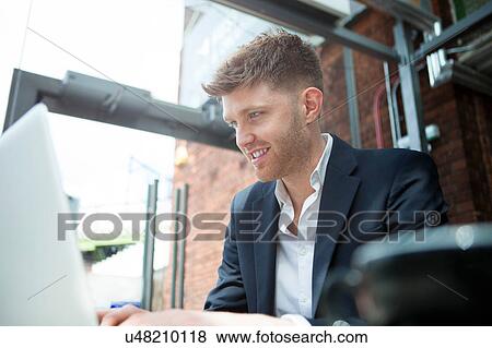 Stock Photo - Businessman working with laptop in cafe. Fotosearch