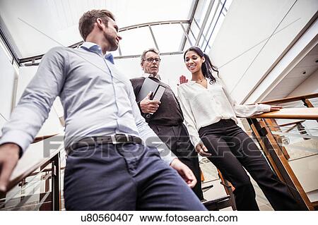 Stock Photo - Businessmen and businesswoman having discussion moving down office stairway. Fotosearch