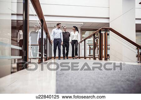 Stock Photography - Businessmen and businesswoman having discussion on office walkway. Fotosearch