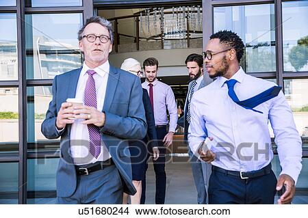 Picture - Businessmen and woman leaving office building. Fotosearch