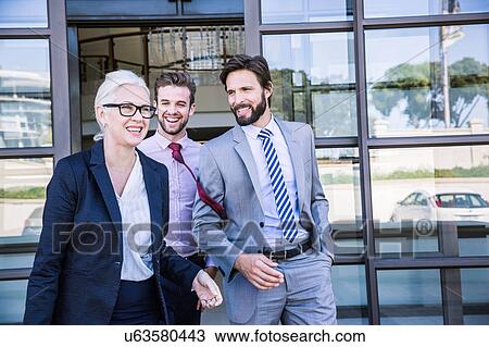 Businessmen and woman talking whilst leaving office building View Large Photo Image Stock Image - Businessmen and woman talking whilst leaving office building. Fotosearch