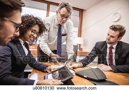Stock Image - Businessmen and woman using digital tablet at boardroom table meeting. Fotosearch