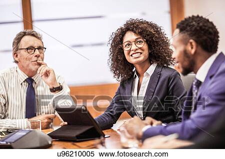 Stock Photography - Businessmen and woman using digital tablet at boardroom table meeting. Fotosearch